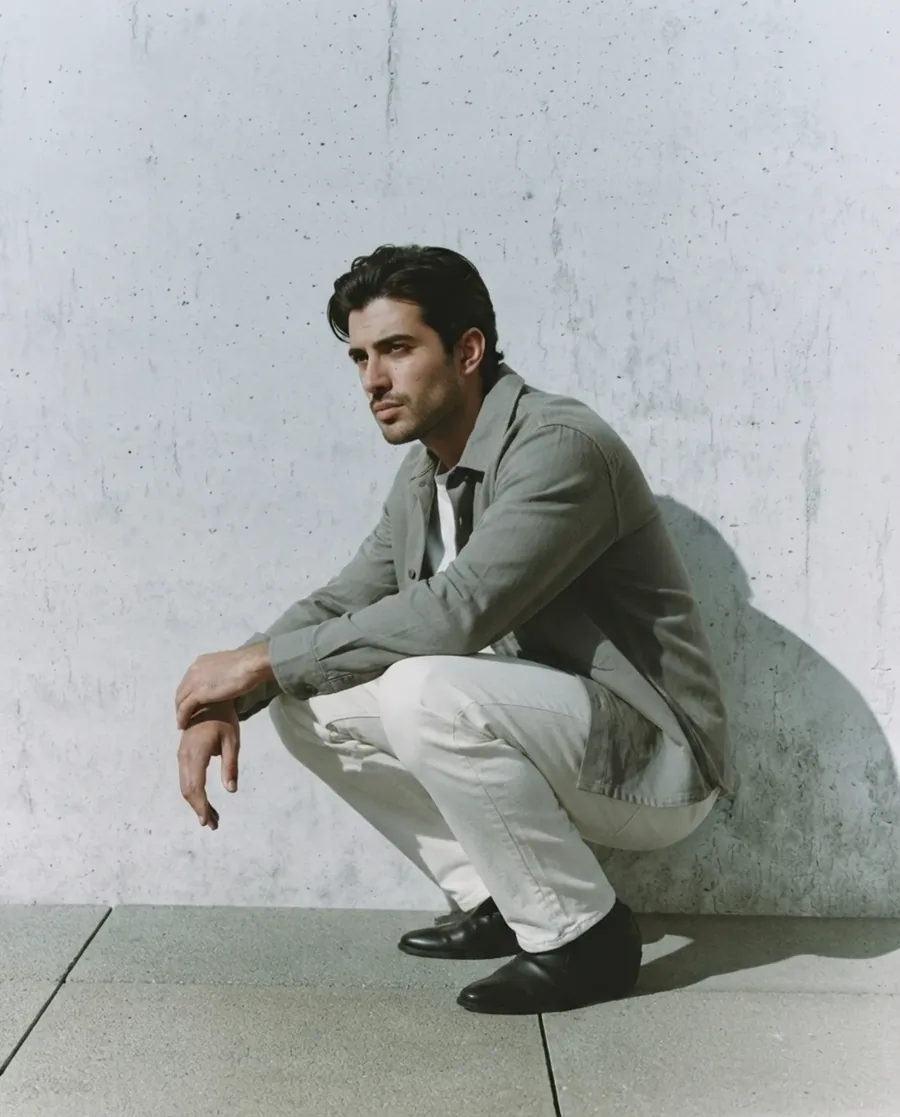 Sage overshirt and cream trousers on an AI model against concrete architecture