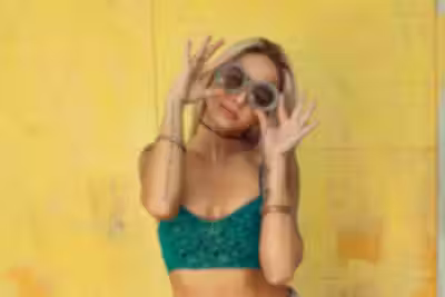 Green knit top on yellow wall — original product photo before AI try-on